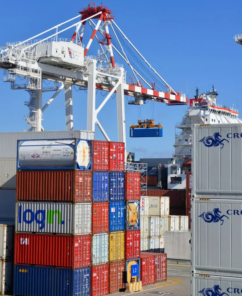 A port crane lifting a container above stacked shipping containers